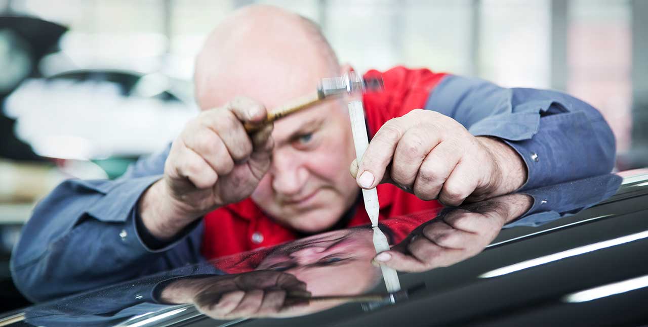 Mechaniker, der eine Delle am Auto repariert - 